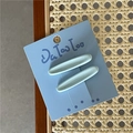 Primer plano de dos pinzas para el cabello ovaladas verde menta sobre fondo de mimbre - Azul
