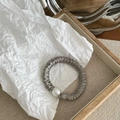Detail view of a gray satin scrunchie featuring a large faux pearl on a wooden tray - Gray Green Thin Style (With Pearl)