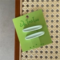 Detalle de dos pinzas ovaladas para el pelo en color verde sobre fondo tejido - Verde