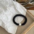 Detalle de un coletero de satén negro con una gran perla blanca en bandeja de madera - Estilo Negro Fino (Con Perla)