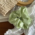 Dettaglio di un elastico per capelli in tessuto vichy verde su sfondo minimalista - Verde