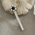 Dettaglio del fermaglio per capelli a fiore argento con perla nera su sfondo in pietra - Fiore d'Argento (Clip a Becco d'Anatra Argentata)