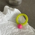 Detailaufnahme des mintgrünen Spiralhaargummis mit pinker Perle auf weißem Papier - Grünes Band Mit Rosaroter Perle