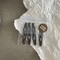 Détail de quatre barrettes à cheveux noires en métal ajouré sous emballage cadeau - Pack de 4 / Noir