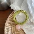 Detail of olive green spiral hair tie with a soft pink heart charm on woven tray - Spiral Telephone Wire Style / Transparent Pink Bead