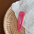 Gros plan d'une barrette BB goutte en métal rose fuchsia sur un fond texturé naturel - Rouge Rose