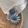 Dettaglio macro di un elastico a spirale azzurro con ciondolo a forma di bacca traslucida - Stile Mirtillo Blu Chiaro