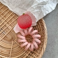 Dettaglio di un elastico a spirale rosa con ciondolo a forma di fragola su vassoio tessuto - Stile Litchi Rosa