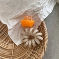 Dettaglio di elastico a spirale con ciondolo arancione in resina su cordoncino beige - Stile Mandarino Sbucciato Arancione