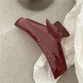 Close-up of shiny dark burgundy hair claw clip with red rhinestones on paper - Burgundy