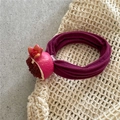 Dettaglio dell'elastico per capelli in tessuto viola con ciondolo a forma di melograno - Melograno