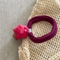 Primo piano dell'elastico per capelli a forma di pitaya rosa su sfondo intrecciato - Frutta