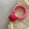 Close-up of pink plush hair tie with realistic red lychee charm and green leaf detail - Lychee