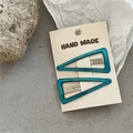 Détail macro de barrettes à cheveux triangle évidé bleu paon sur carte en papier - Triangle Bleu Lac