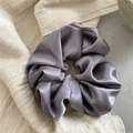 Macro detail of dark grey satin scrunchie showing smooth fabric texture and soft pleats - Gray