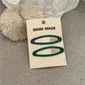 Dettaglio di fermagli ovali in resina verde scuro su un cartoncino beige fatto a mano - Stile Ovale / Verde