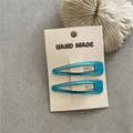 Close-up of handmade turquoise drop-shaped hair clips on a natural paper card - Lake Blue Water Drop