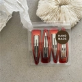 Set of four amber red teardrop hair clips in handmade packaging on stone texture - Transparent Red Coffee