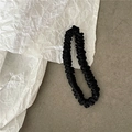 Detailed view of elegant black silk scrunchie with fine pleats and lustrous fabric texture - Black