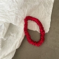 Macro shot of red pleated silk scrunchie showing glossy texture and elegant design - Red