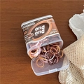 Macro shot of colorful TPU elastic hair bands in a transparent box on wooden table - Coffee Series