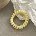 Detailansicht eines hellgelben Spiral-Haargummis auf einer minimalistischen Fläche - Hellgelb