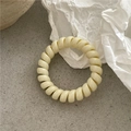 Détail d'un chouchou spirale crème sur un fond texturé minimaliste avec lumière douce - Blanc Cassé