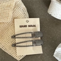 Detailed view of two dark grey translucent resin hair clips on handmade paper card - Gray
