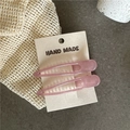 Detail of two translucent light pink resin hair clips on a handmade card packaging - Pink