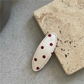 Detalle de una pinza para el pelo ovalada en tela crema con lunares rojos sobre piedra beige - Pinza BB Ovalada / Blanco con lunares rojos