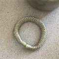 Detailed view of an olive green pleated satin scrunchie with a matte cylinder bead detail - Green