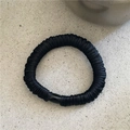Close-up of black pleated satin hair tie with smooth connector on grey stone surface - Black