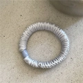 Close-up of a silver-gray pleated scrunchie with a glossy light blue resin bead detail - Blue