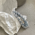 Gros plan d'une barrette BB de luxe perlée de cristaux bleu clair sur fond minimaliste - Larme Bleue