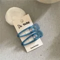 Detail of blue translucent water-drop hair clips on card packaging with metallic duckbill clip - Waterdrop Duckbill Clip / Blue