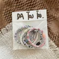 Detail of 5-piece cream color elastic hair ties with colorful resin beads in packaging - Iridescent White