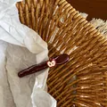 Detalle macro de una pinza para el pelo con manzana roja brillante en cesta tejida - Estilo de Decoración de Manzana Blanca / Rojo Oscuro