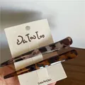 Dettaglio di due fermagli per capelli leopardati e resina ambrata su cartoncino bianco - Stile leopardato a contrasto cavo corto
