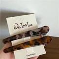 Vista dettagliata di due fermagli per capelli in resina tartarugata su cartoncino - Stile leopardato a contrasto piatto
