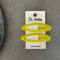 Detail of yellow flocked oval BB hair clips on white card with metal base texture - Yellow
