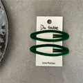 Close-up of two dark green flocked geometric oval snap hair clips on branded card - Dark Green
