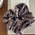 Detailed view of velvet polka dot scrunchie placed on vintage book with soft lighting - Brown