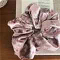 Detail of soft velvet scrunchie with polka dot pattern on a wooden surface - Pink