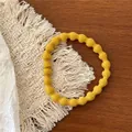 Detailed shot of yellow elastic hair band with beaded texture on woven mat - Dark Yellow
