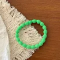 Detail of a grass green ribbed elastic hair scrunchie on a woven mat and wood surface - Neon Green