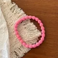 Gros plan sur un élastique à cheveux rose texturé posé sur une table en bois - Deep Rose Pink