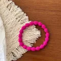Gros plan d'un chouchou élastique rouge rose texturé sur un support tissé beige - Rose Rouge