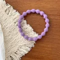 Detailed close-up of a purple elastic wavy hair tie placed on a stylish woven coaster - Light Purple