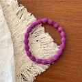 Detailed macro view of a purple wavy elastic hair tie on a decorative woven mat - Deep purple