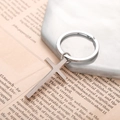 Porte-clés croix minimaliste en acier inoxydable argenté sur fond en marbre blanc - Argenté